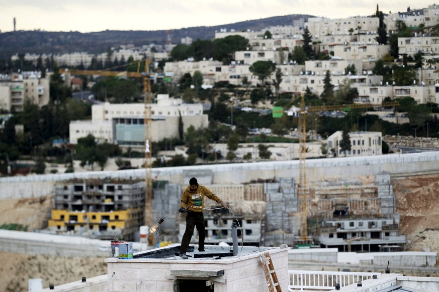 FILE PHOTO: A man works on a roof in Ramat Shlomo, a religious Jewish settlement in an area of the occupied West Bank that Israel annexed to Jerusalem November 17, 2015. REUTERS/Ronen Zvulun/File Phot ...