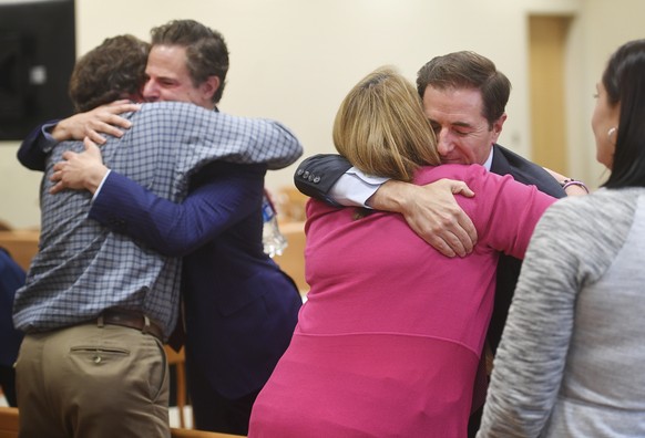 Plaintiff William Sherlach, left, hugs attorney Josh Koskoff while plaintiff Nicole Hockley hugs attorney Chris Mattei following the jury verdict and reading of monetary damages in the Alex Jones defa ...