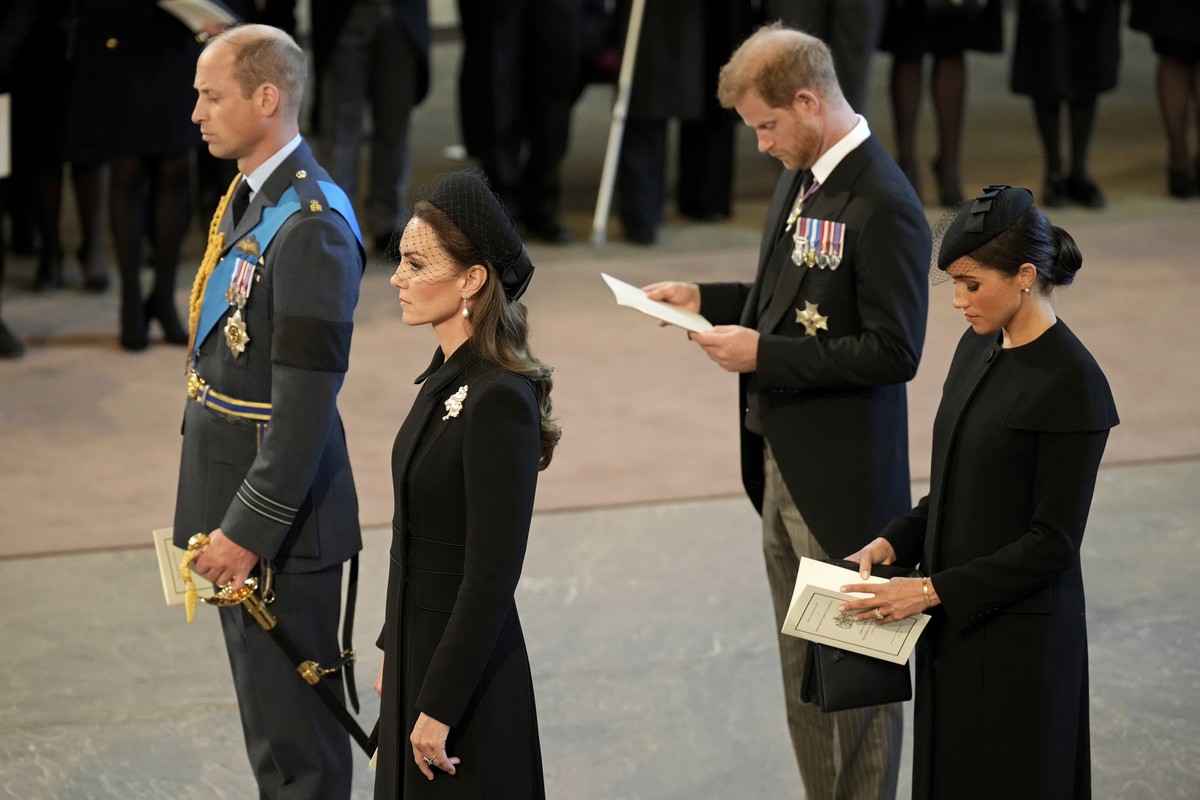 Britain's Prince William, left, Kate, Princess of Wales, second left, Prince Harry, and his wife Meghan, the Duchess of Sussex, right, pay their respects to Queen Elizabeth II as the coffin rests ...
