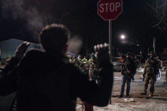 epa12650415 Community member raises his hands during a confrontation with federal agents in a residential neighborhood in Minneapolis, Minnesota, USA, 14 January 2026. As part of a federal immigration ...
