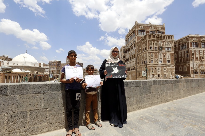 epa06999446 Yemeni female activist Haifa Subay (R) and children hold pro-peace placards during a campaign calling for peace in the war-torn country, in the old quarter of Sana&#039;a, Yemen, 05 Septem ...