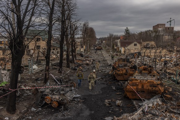 epa09874820 Members of the Ukrainian military walk past destroyed Russian military machinery on the street, in Bucha, the town which was retaken by the Ukrainian army, northwest of Kyiv, Ukraine, 06 A ...