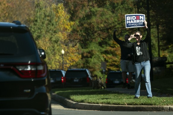 In this image made through the window of the press vehicle accompanying the motorcade carrying President Donald Trump, people hold signs at the entrance of Trump National Golf Club, Sunday, Nov. 8, 20 ...