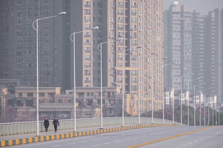 People wearing face masks walk down a deserted street in Wuhan in central China&#039;s Hubei Province, Tuesday, Jan. 28, 2020. China&#039;s death toll from a new viral disease that is causing a global ...