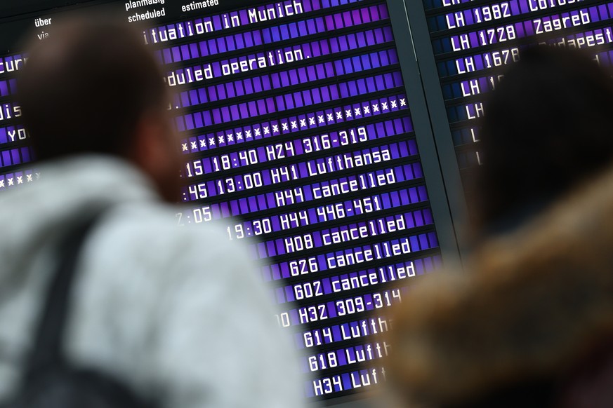 epa11084875 Passengers look at information boards showing cancelled flights at Munich Airport in Munich, Germany, 17 January 2024. Slippery conditions due to freezing rain and ice formation cause traf ...