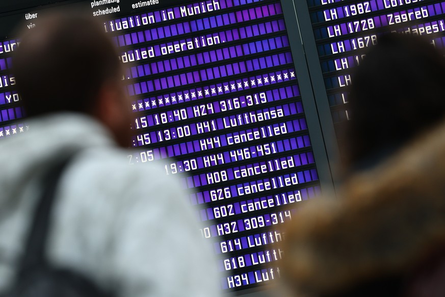 epa11084875 Passengers look at information boards showing canceled flights at Munich Airport in Munich, Germany, January 17, 2024. Slippery conditions due to freezing rain and icing cause hits...
