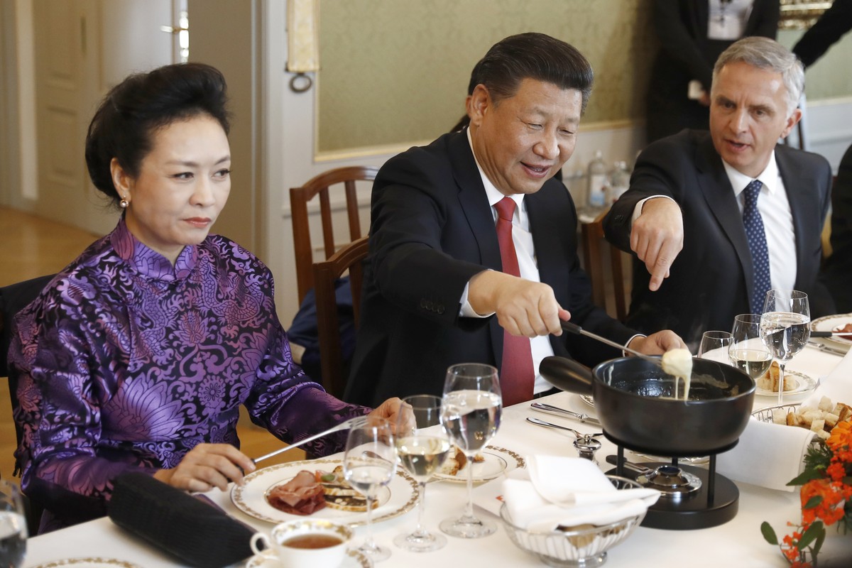 China's President Xi Jinping, center, Xi's wife Peng Liyuan, left, and Swiss Foreign Minister Didier Burkhalter eat Swiss cheese fondue during lunch during Xi's two days state visit to  ...