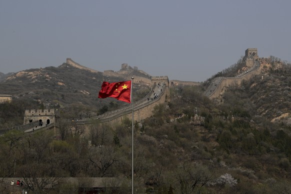 A Chinese national flag flutters against the Badaling Great Wall of China after it reopened business for visitors weeks ago in Beijing, Tuesday, April 14, 2020. China reported dozens of new virus case ...