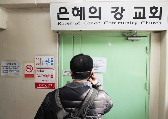 epa08296731 A man takes a photograph at the gate to the temporarily closed River of Grace Community Church in Seongnam, South Korea, 16 March 2020. The church will be closed until March 22 after 46 pe ...