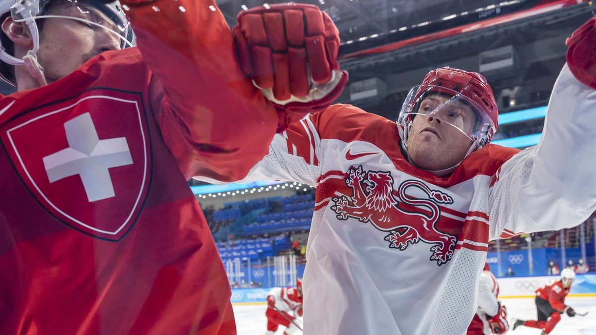epa09750107 Denmark's Julian Jakobsen (R) checks Switzerland's Fabrice Herzog (L) during the Men's Ice Hockey preliminary round game between Switzerland and Denmark at the Beijing 2022  ...
