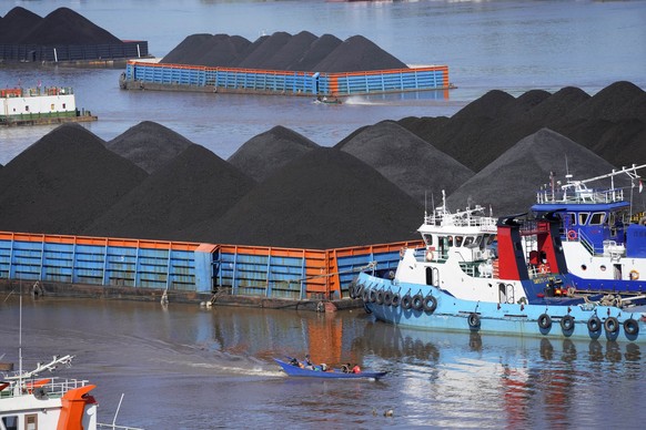 FILE- Boats cruise near barges fully loaded with coal on the Mahakam river in Samarinda, East Kalimantan, Indonesia, on Dec. 19, 2022. (AP Photo/Dita Alangkara, File)