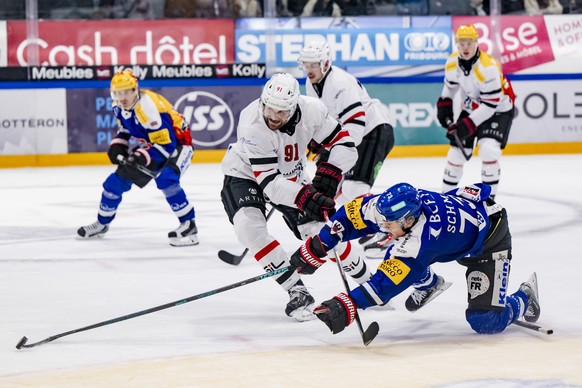 Fabian Heldner (LHC), gauche, lutte pour le puck avec Sandro Schmid (HCFG), droite, lors du match du championnat suisse de hockey sur glace de National League entre HC Fribourg-Gotteron et Lausanne HC ...