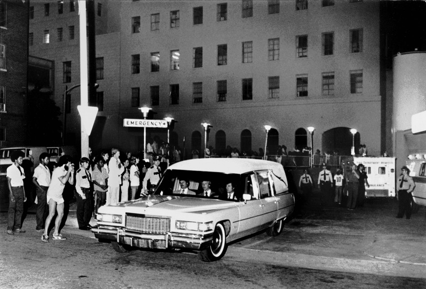 Aug. 16, 1977 - Memphis, Tennessee, U.S. - People waited outside near the emergency entrance at Baptist Memorial Hospital as the hearse carrying the body of Elvis Presley leaves the hospital August 16 ...