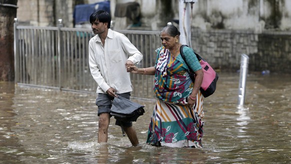 A man holds the hand of an elderly woman and helps her past a waterlogged street in Mumbai, India, Thursday, June 7, 2018. India&#039;s commercial capital has been hit by heavy rainfall, disrupting no ...