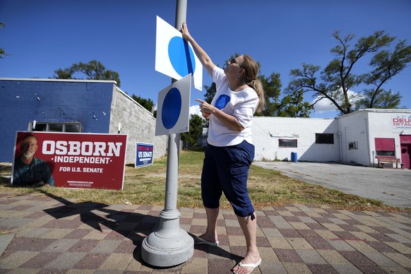 Ruth Huebner-Brown hangs a blue dot campaign sign, that represent Democratic-voting households in a state surrounded by Republican red, before a blue dot campaign sign get-together, Tuesday, Sept. 24, ...