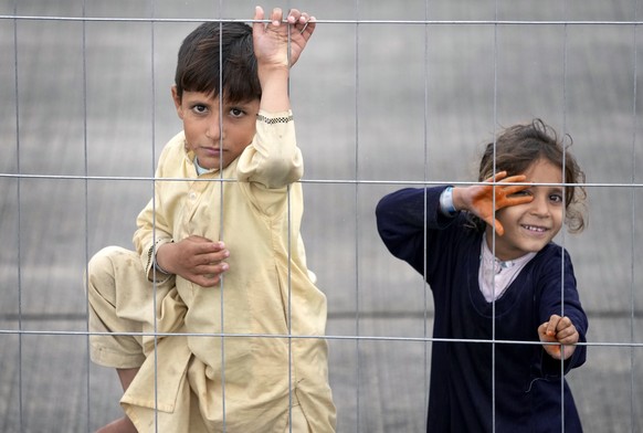 Two kids stay behind a fence at the Ramstein U.S. Air Base in Ramstein, Germany, Monday, Aug. 30, 2021. The largest American military community overseas houses thousands Afghan evacuees in a tent city ...
