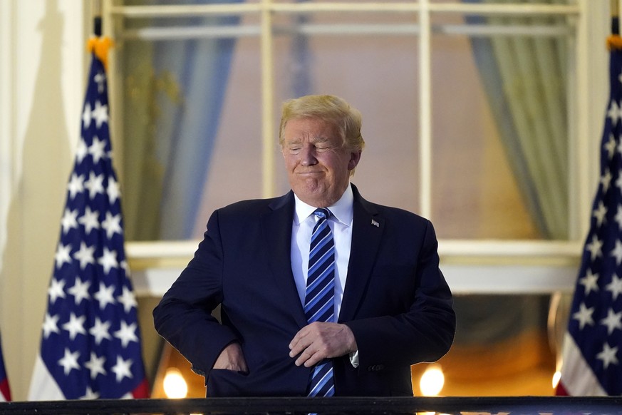 President Donald Trump puts his face mask into his pocket as he stands on the balcony outside of the Blue Room as returns to the White House Monday, Oct. 5, 2020, in Washington, after leaving Walter R ...