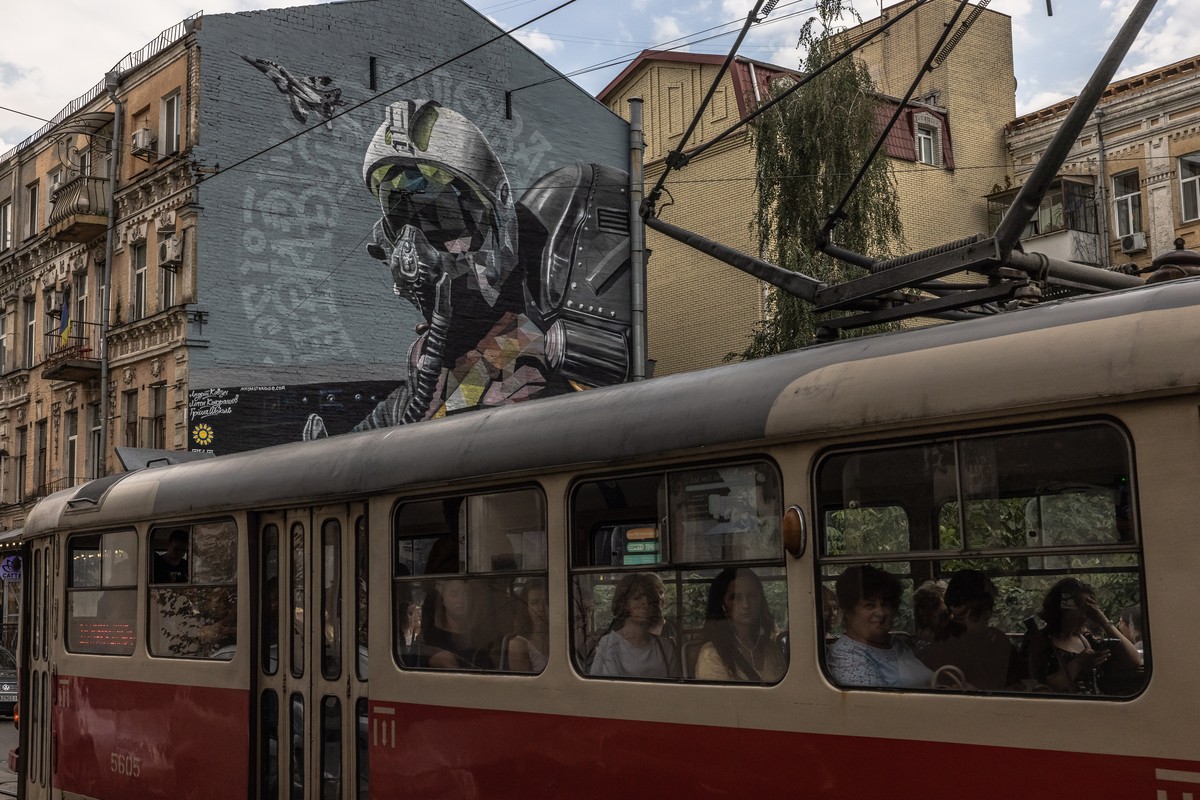 epa10145785 People ride on a tram past a mural called 'The ghost of Kyiv', dedicated to Ukrainian air force pilots who were defending the sky over Kyiv during the Russian attacks, in downtow ...