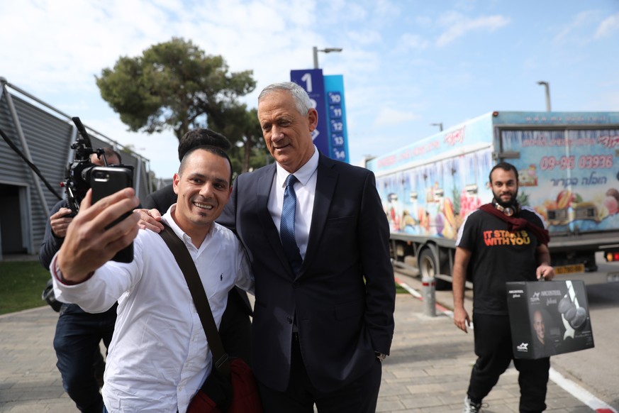 epa07478339 Leader of the Blue and White party prime minister candidate Benny Gantz (C) takes a selfie with a person before a press conference in Tel Aviv, Israel, 01 April 2019. Benny Gantz and Yair  ...