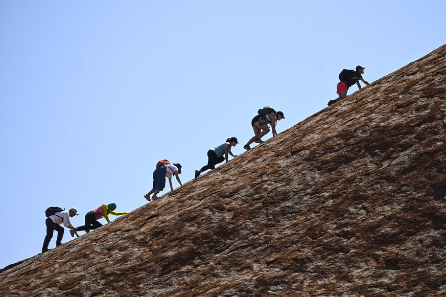 epa07948049 Tourists climb Uluru, Australia's iconic sandstone formation, in Uluru-Kata Tjuta National Park in Northern Territory, Australia, 25 October 2019. Tourists have been flocking to Uluru ...