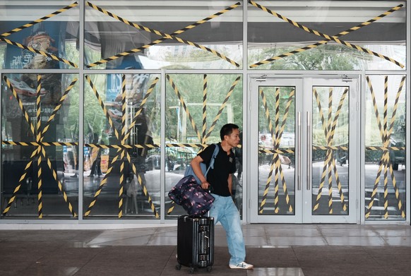 A passenger walks by a closed door of a coach station where all glass windows and doors are reinforced with protective tape in preparation for the approaching Typhoon Dolphin in Hangzhou in eastern Ch ...