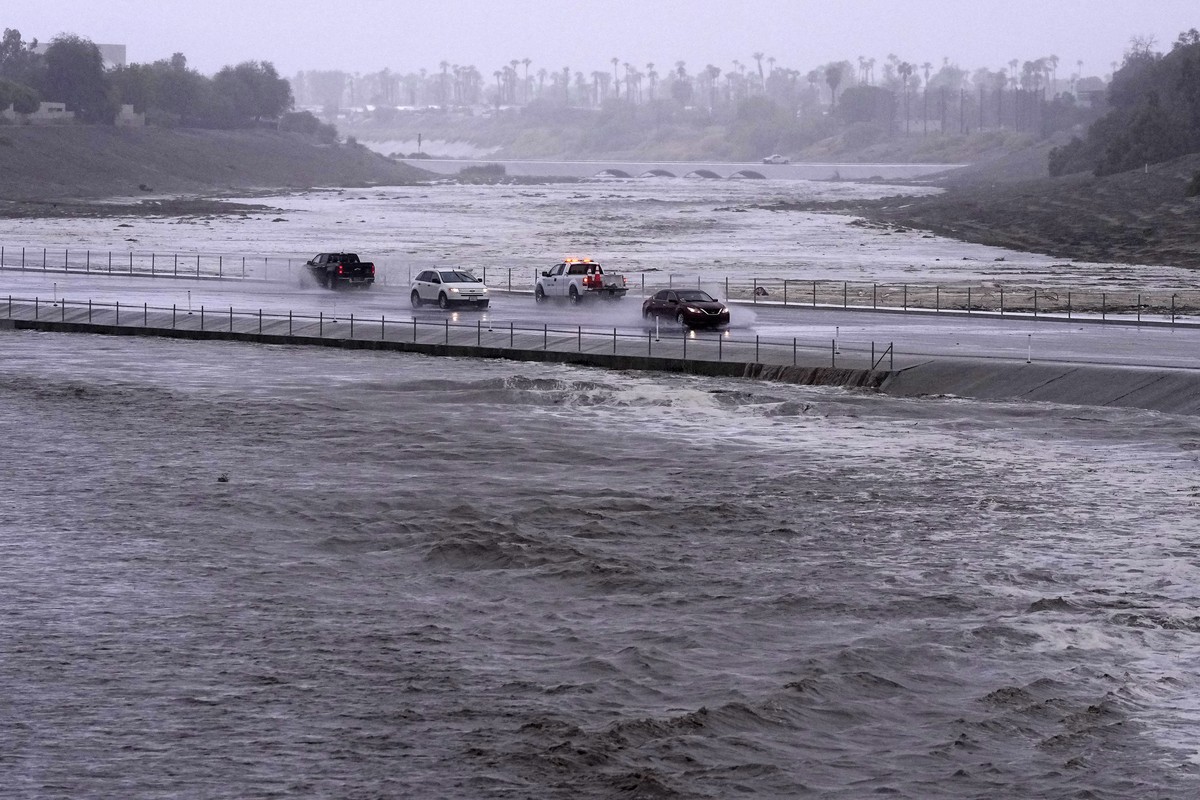 FILE - Vehicles cross over a flood control basin that has almost reached the street, Sunday, Aug. 20, 2023, in Palm Desert, Calif. Scientists figure a natural El Nino, human-caused climate change, a s ...