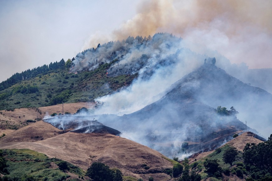 epa07779388 Smoke rises over a forest fire near of the village of Moya, in Gran Canaria island, Canary Islands, Spain, 18 August 2019. About 4,000 people have been evacuated from the area due to a for ...