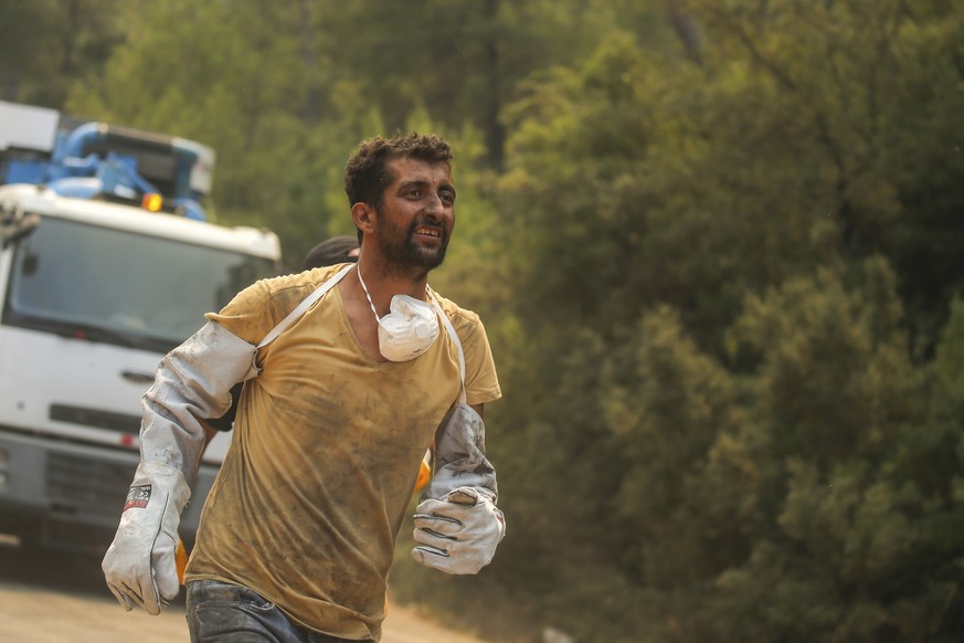 A Turkish volunteer runs as they head to fight wildfires in Turgut village, near tourist resort of Marmaris, Mugla, Turkey, Wednesday, Aug. 4, 2021. Hundreds of volunteers have joined efforts to conta ...