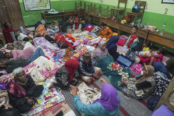 People rest at a school turned into temporary shelter for those evacuated from their homes following the eruption of Mount Semeru, in Lumajang, East Java, Indonesia, Sunday, Dec. 4, 2022. Indonesia&#0 ...