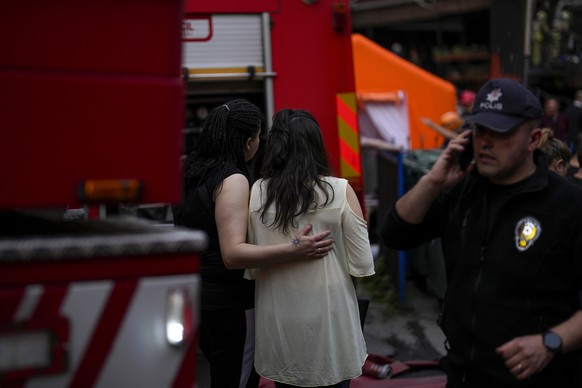 Two women gather as firefighters and emergency teams work in the aftermath of a fire in a nightclub in Istanbul, Turkey, Tuesday, April 2, 2024. A fire at an Istanbul nightclub during renovations on T ...