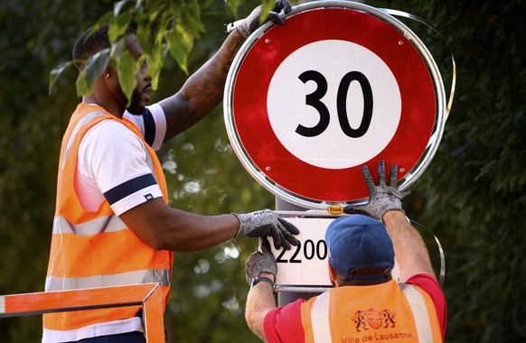 Deux employes de la ville de Lausanne mettent en place un panneau de circulation signalant l&#039;interdiction de rouler a plus de 30km/h, de 22h00 a 06h00, ce lundi 13 septembre 2021 dans une rue de  ...