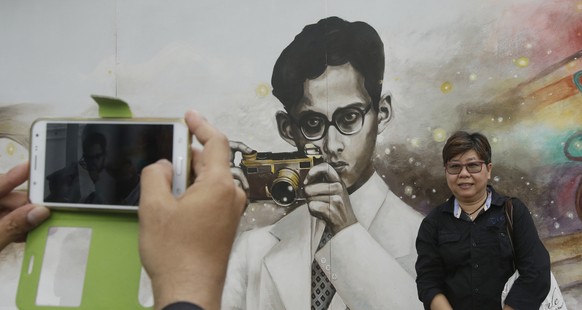 People take a picture of a drawing portrait of the late Thai King Bhumibol Adulyadej in Bangkok, Thailand, Tuesday, Oct. 18, 2016. Bhumibol was 8 when he got hold of his first camera - a Coronet Midge ...