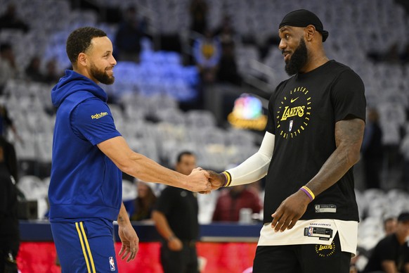 Los Angeles Lakers forward LeBron James, right, shakes hands with Golden State Warriors guard Stephen Curry, left, during warm ups before an NBA basketball game ,Wednesday, Dec. 25, 2024, in San Franc ...