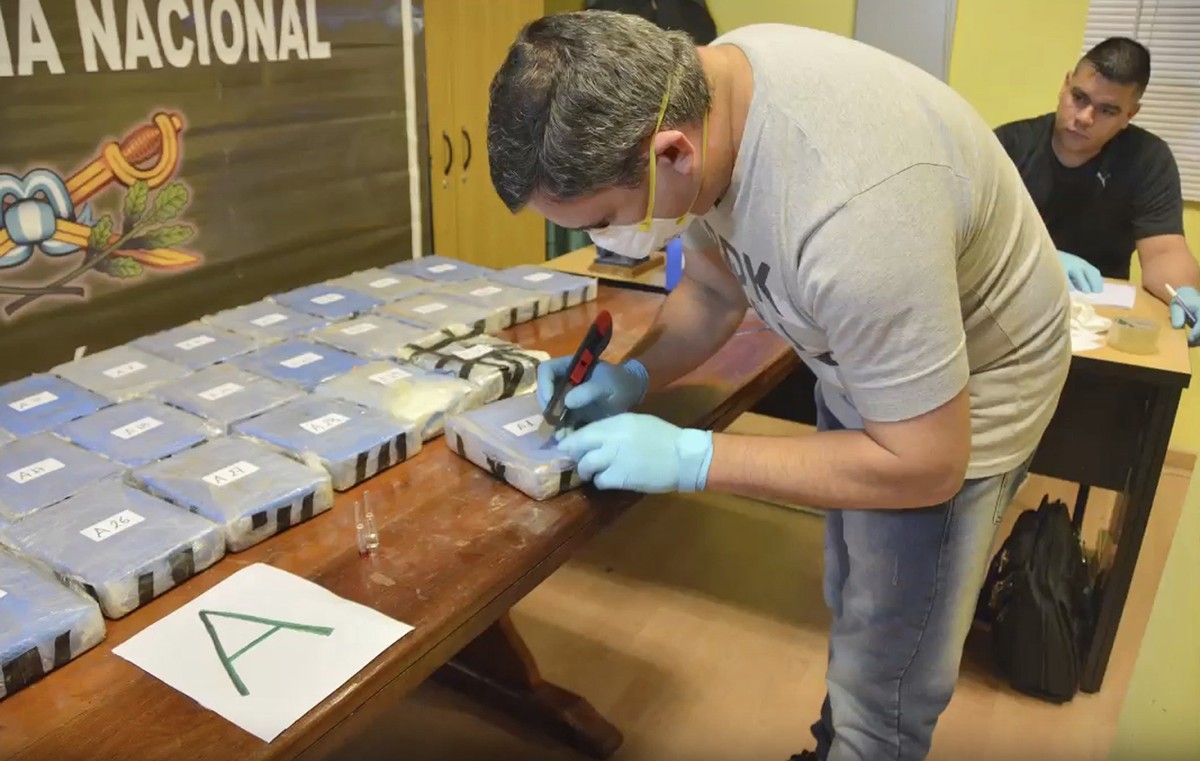 In this Dec. 14, 2016, photo and released on Feb. 22, 2018, by the Argentine Security Ministry, a police officer opens up a package of cocaine found in an annex building Russian embassy in Buenos Aire ...