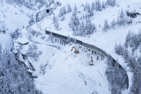 epaselect epa06429366 A digger at work in the aftermath of an avalanche crossing the road on the way between Taesch and Zermatt, in Zermatt, Switzerland, 10 January 2018. Due to heavy snowfall and rai ...