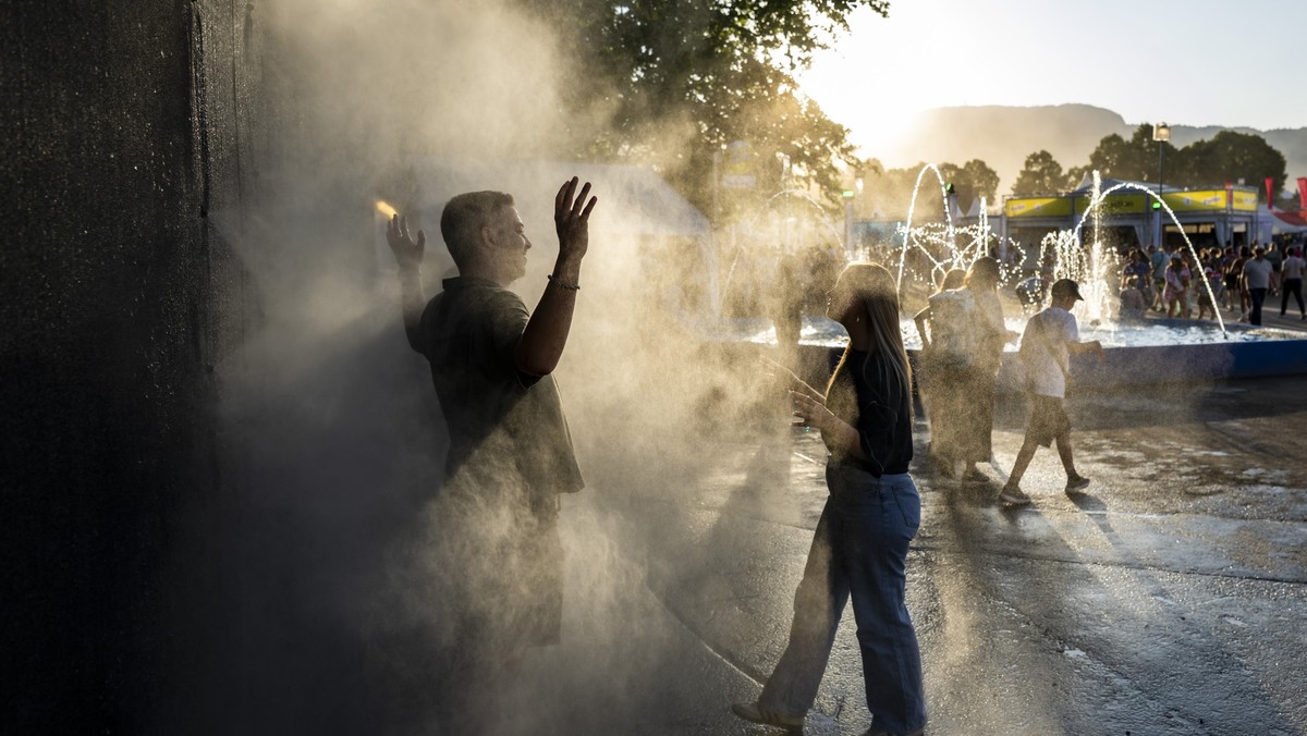 KEYPIX - Two festivalgoers cool off with a mist of water during the 49th edition of the Paleo Festival, in Nyon Switzerland, Friday, July 24, 2026. (KEYSTONE/Jean-Christophe Bott)