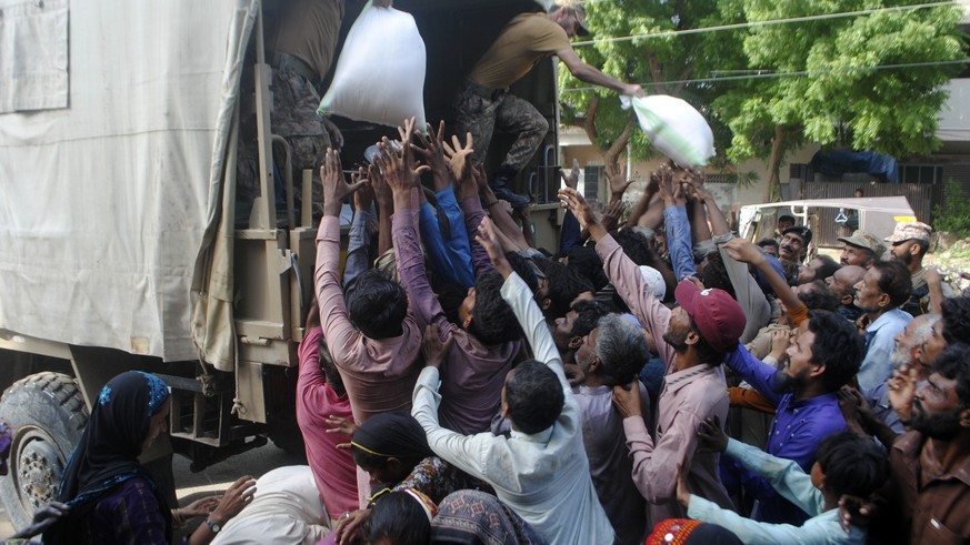 FILE - Army troops distribute food and other stuff to displaced people in a flood-hit area in in Hyderabad, Pakistan, Aug. 27, 2022. The flooding has all the hallmarks of a catastrophe juiced by clima ...