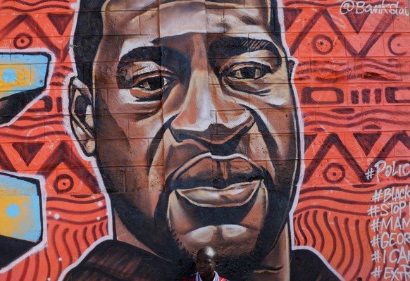 epa08464355 A man seats to a graffiti in memory of the late US George Floyd painted on a perimeter wall by a group of Kenyan graffiti artists in support of the Black Lives Matter movement as their way ...