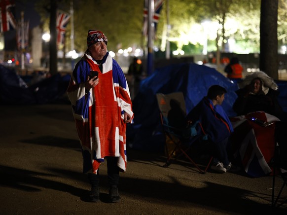 epa10605152 A man walks past tents and people who have lined up to see the coronation of Britain's King Charles III on the Mall, near Buckingham Palace in London, UK, 02 Ma...