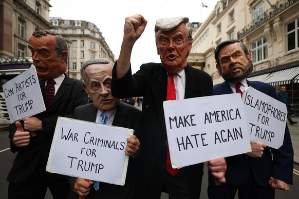 epa12385034 Protesters wearing masks depicting world leaders including US President Trump (2-R) hold up placards during a &#039;Stop Trump Coalition&#039; mass demonstration against the state visit to ...