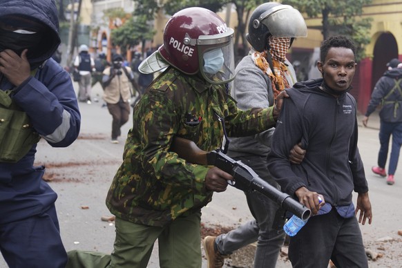 Kenya anti riot police arrest a man during a protest in Nairobi, Kenya Thursday, June 27, 2024. Thousands of protesters stormed and burned a section of Kenya&#039;s parliament Tuesday to protest tax p ...