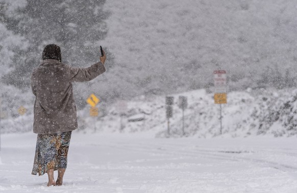 A visitor stands on a snow-covered road while taking a selfie in the Angeles National Forest near La Canada Flintridge, Calif., Thursday, Feb. 23, 2023. (AP Photo/Jae C. Hong)