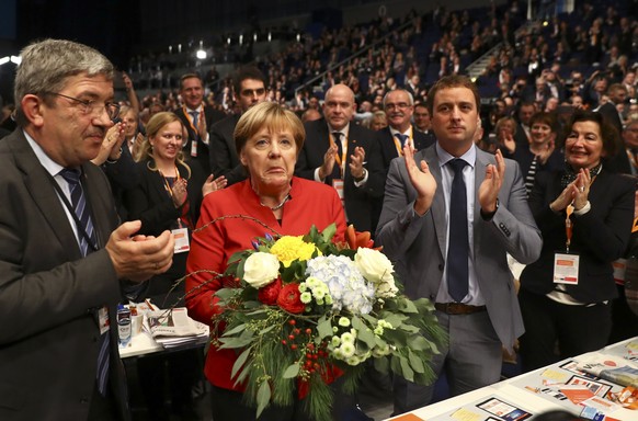 German Chancellor and leader of the conservative Christian Democratic Union party CDU Angela Merkel receives flowers after she was re-elected as chairwoman at the CDU party convention in Essen, German ...