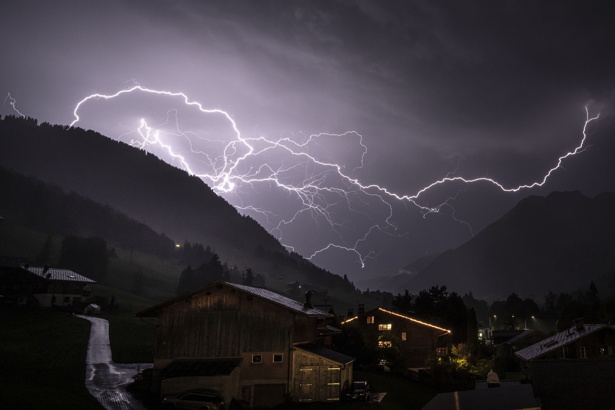 Ein verzweigter Blitz durchschneidet den Gewitterhimmel ueber dem Tal in Richtung Gsteig, aufgenommen von Gstaad (BE), Schweiz, am Donnerstag, 16. Juli 2026. Waehrend eine Hitzewelle weiterhin Teile d ...