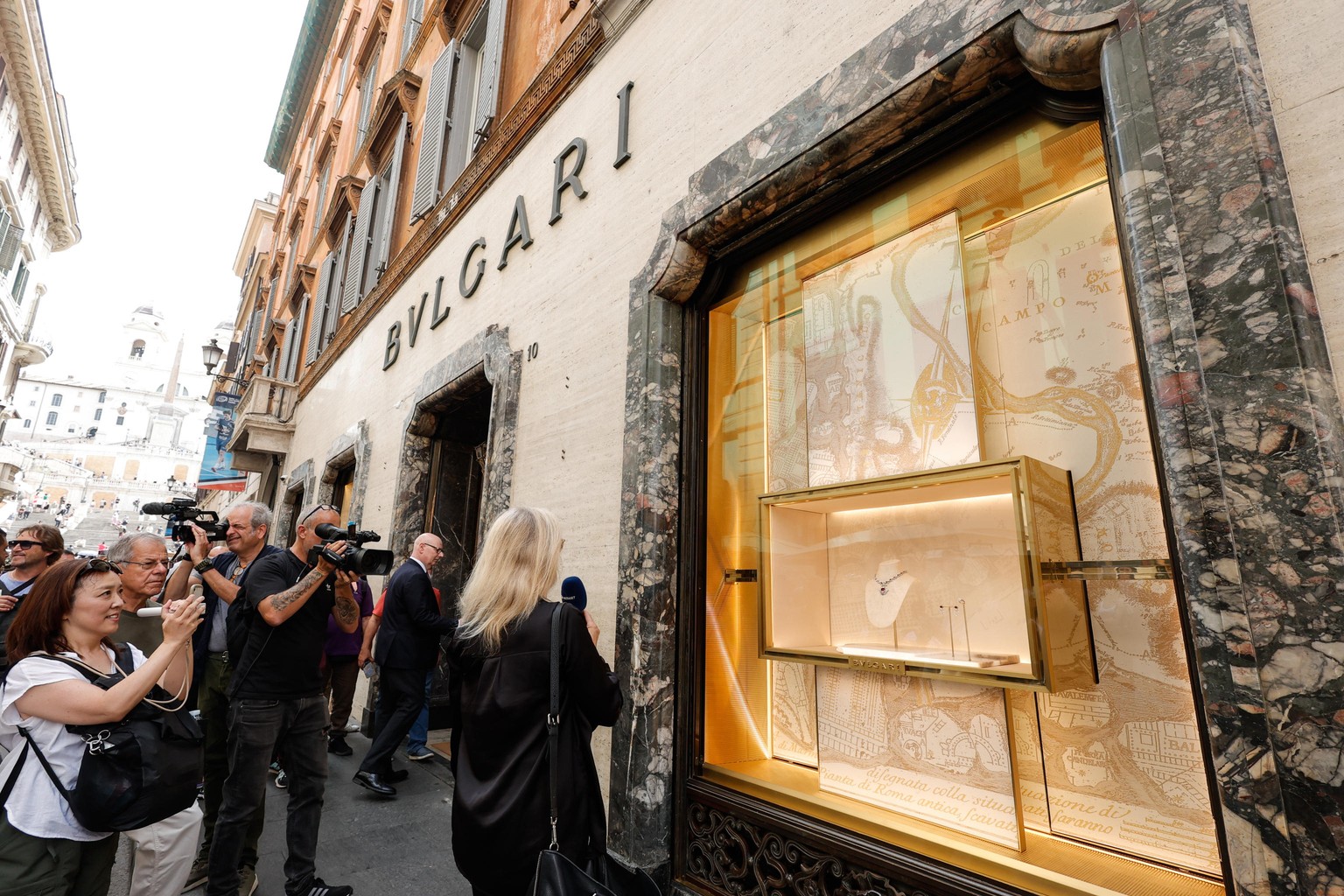epa11399442 People stand outside the Bulgari store in via Condotti, after a theft worth 500,000 euros was carried out during the night in Rome, Italy, 09 June 2024. The thieves entered the jewelry sto ...