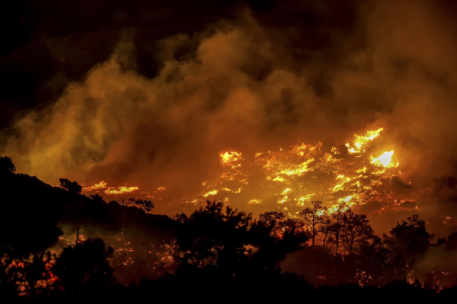 Fire burns in the Ahlia area near the port town of Ierapetra on the south coast of Crete island, Greece, late Wednesday, July 2, 2025, prompting the evacuation of villages and hotels in the region, au ...