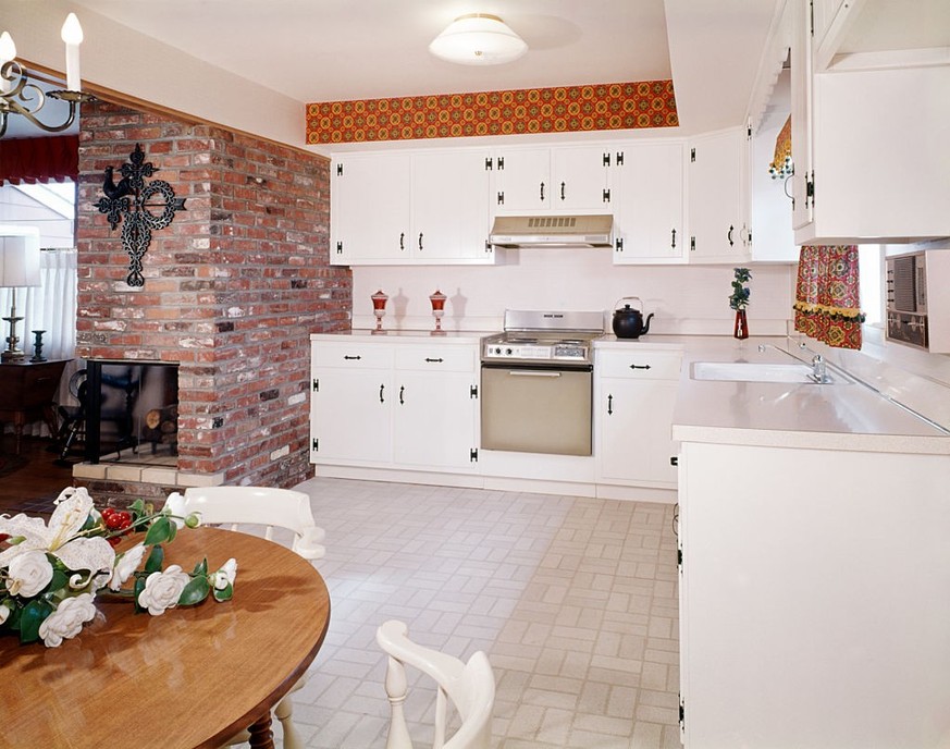 1969 KITCHEN INTERIOR WITH BRICK WALL AND WHITE COUNTRY CABINETS BLACK HINGES HARDWARE (Photo by H. Armstrong Roberts/ClassicStock/Getty Images)