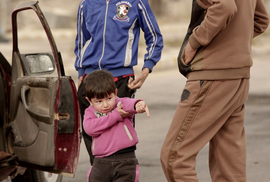 jIn this Sunday, March 20, 2016 photo, an Iraqi boy pantomimes firing a rifle as a convoy of families fleeing Islamic State-held Hit, Iraq, wait at a checkpoint on the western edge of Ramadi, Iraq. Ba ...