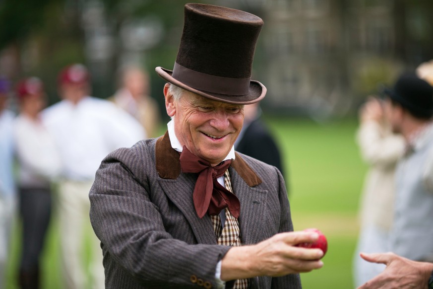 FILE - British author and former politician Jeffrey Archer hands over a cricket ball before umpiring a Victorian-era costume themed cricket match on a wicket in Vincent Square in central London on May ...