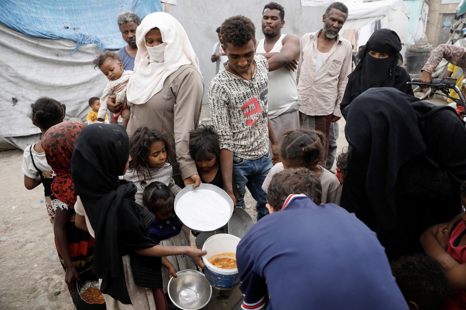 epa10814056 Yemenis wait with their pots to receive free food provided by a charitable kitchen at a makeshift camp for Internally Displaced Persons (IDPs) in Sana&#039;a, Yemen, 22 August 2023. The Wo ...